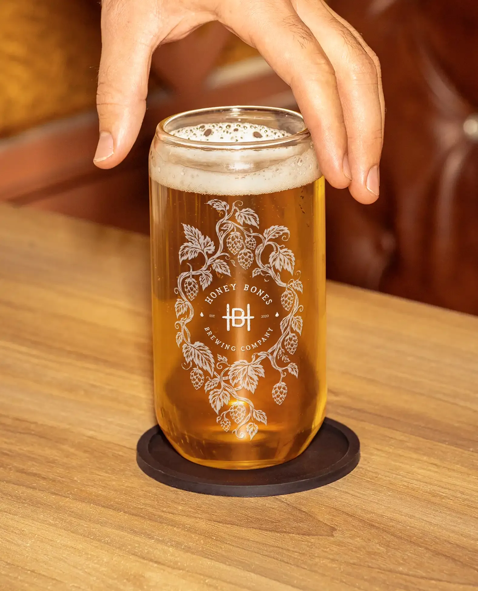 Honey Bones monogram etched inside a hop wreath on a beer glass