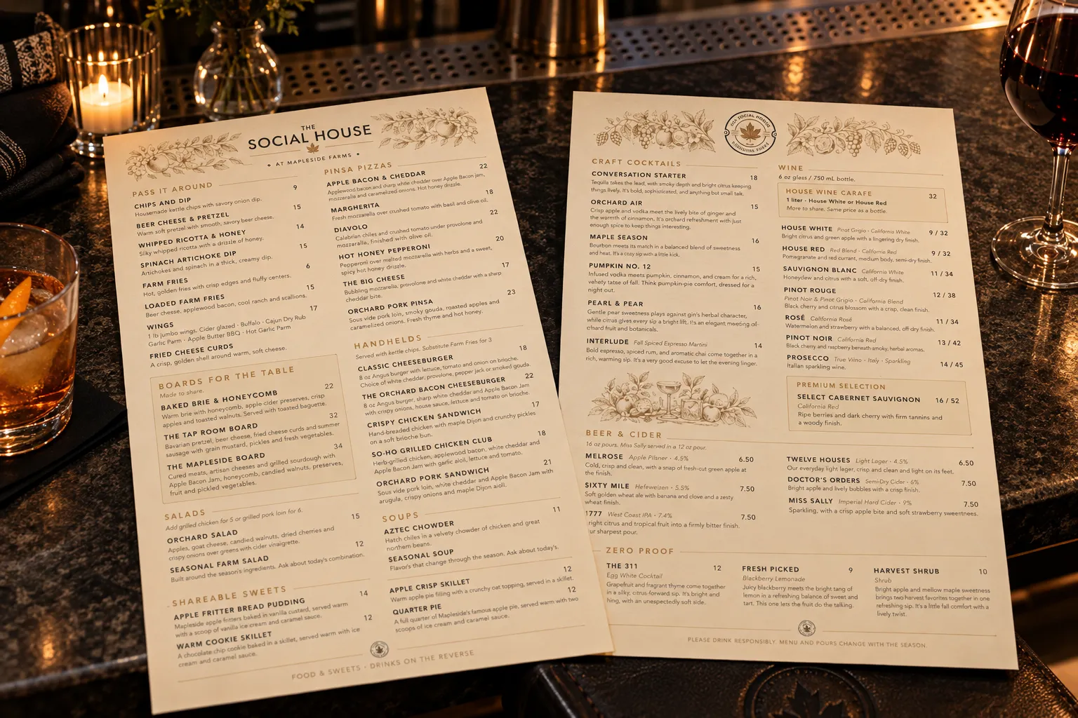 The Social House food and drink menus laid open on a bar top beside a cocktail and a glass of red