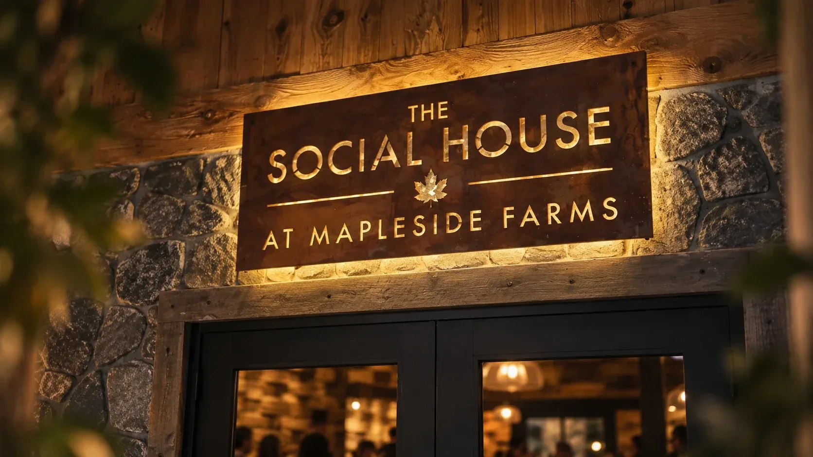 The Social House wordmark cut from rusted steel and backlit above the entrance doors