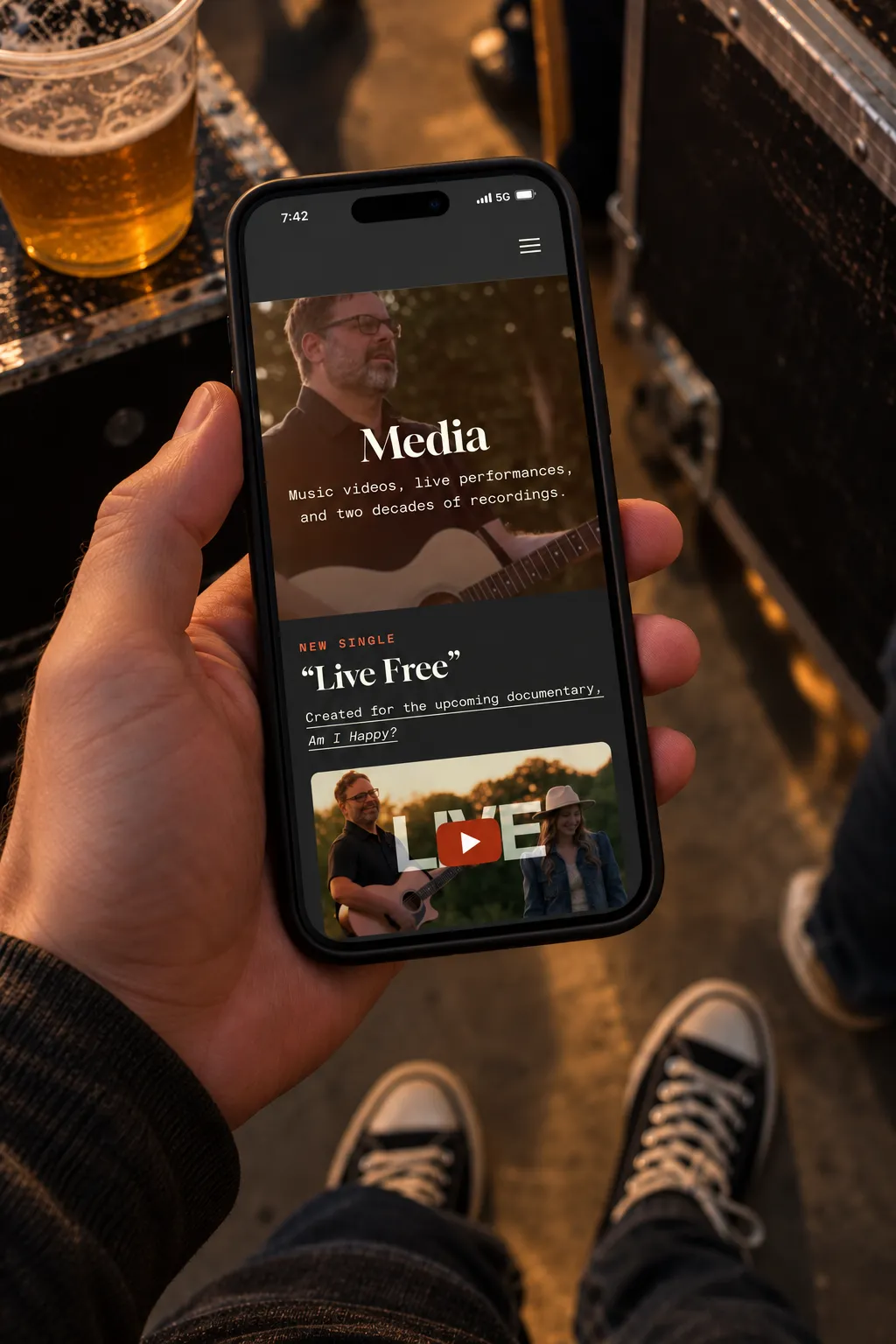 The media page of the Galen Marten site held on a phone at a bar
