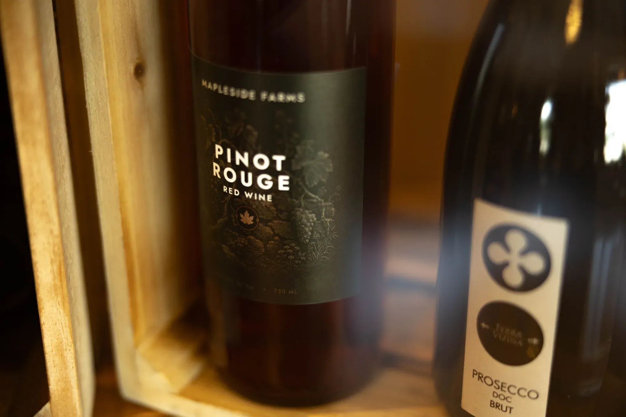 A bottle of Pinot Rouge and a bottle of Prosecco in a wooden crate on the bar