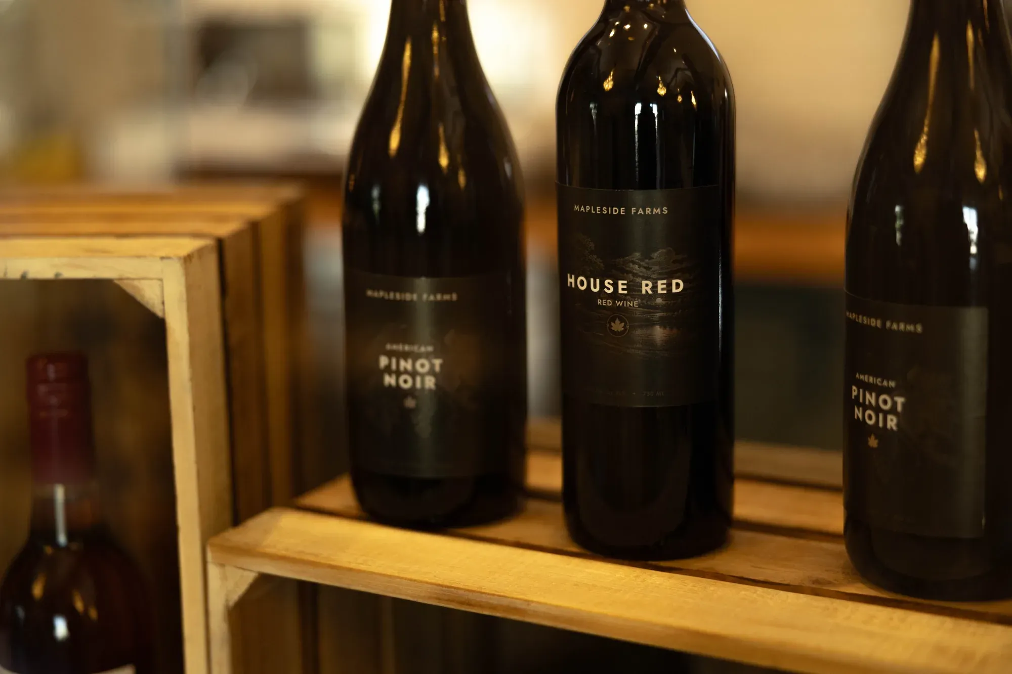 Pinot Noir, House Red and a second Pinot Noir lined up on a wooden shelf behind the bar